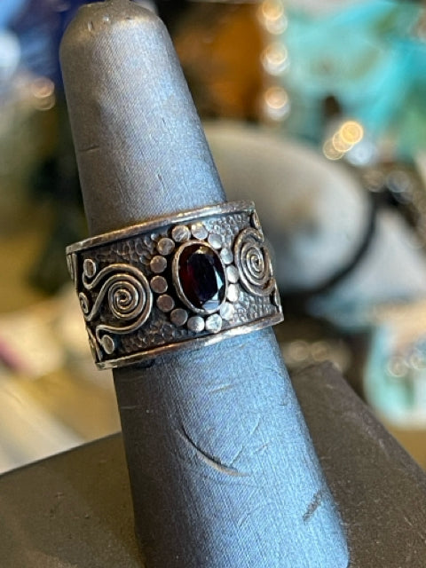 925 Sterling Silver Ring

Wide band w Scroll Work Garnet like oval center stone 

Ring Sz appx 7